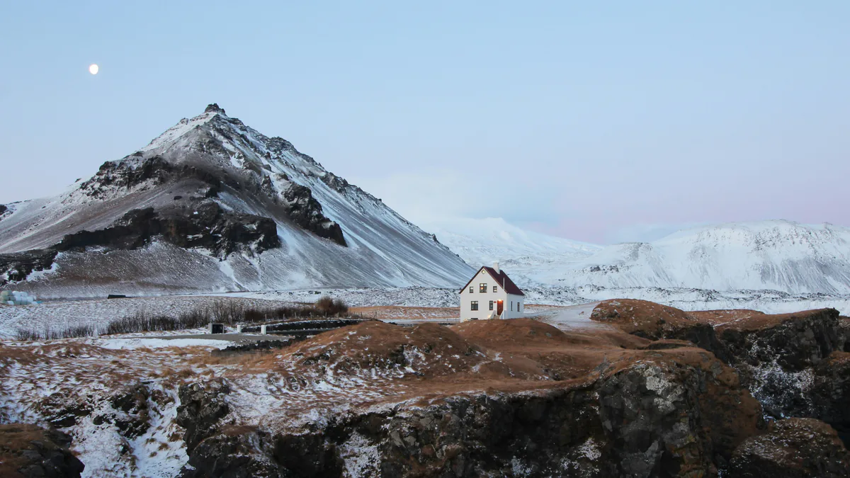Paisaje nevado de montaña y una casa en Islandia