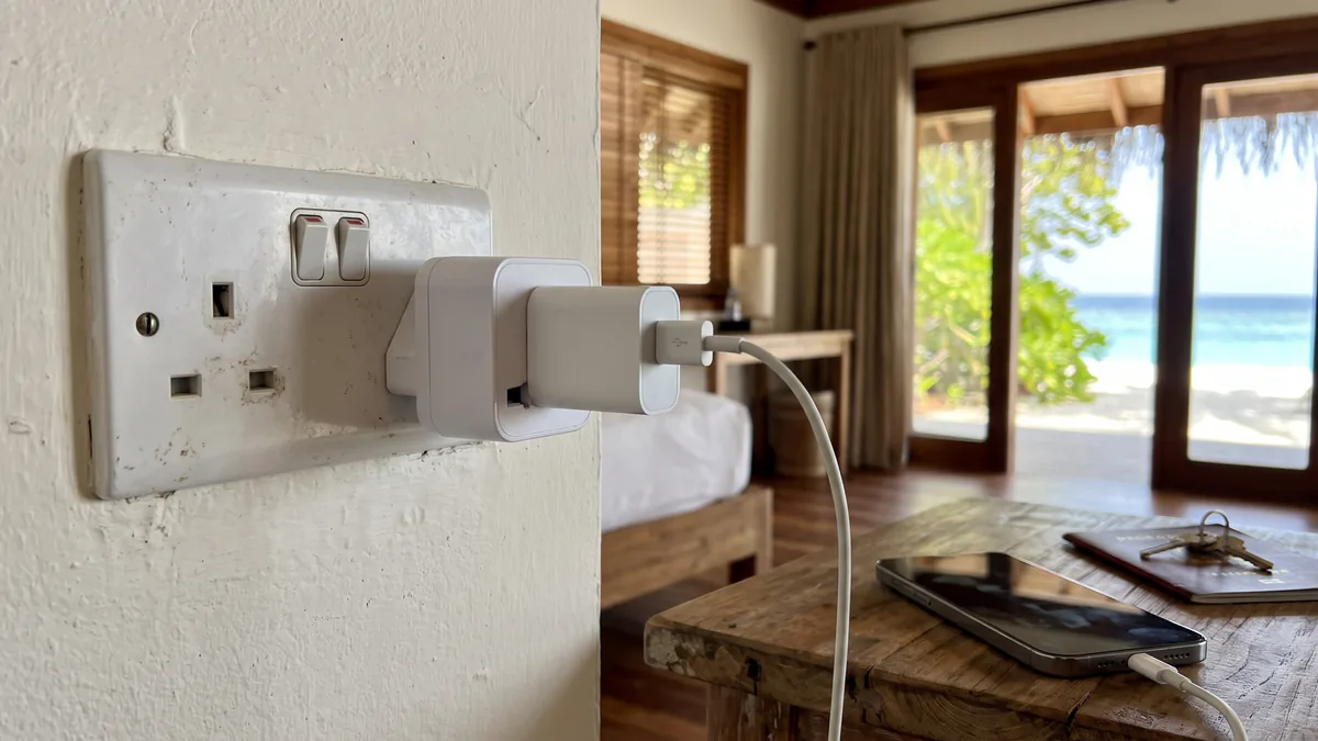 Adaptador europeo conectado a un enchufe tipo G en una habitación de Maldivas