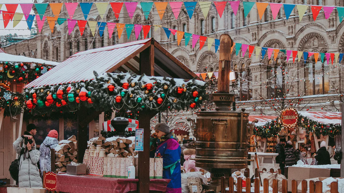 Puestos de un mercado navideño cubierto de nieve frente a un edificio histórico